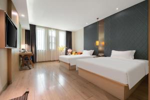 a hotel room with two beds and a flat screen tv at Ibis Styles XM Zhongshan Hotel in Xiamen