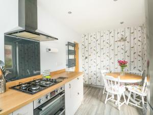 a kitchen with a stove and a table with chairs at Snuffling Hedgehog in Lincoln