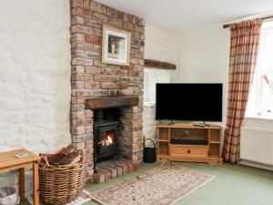 a living room with a brick fireplace with a television at Strathannan in Moffat