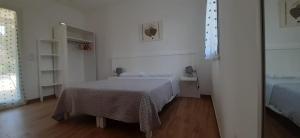 um quarto branco com uma cama e piso em madeira em Molto Benissimo em Otranto