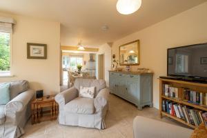 a living room with two chairs and a flat screen tv at Willow House in Aldringham