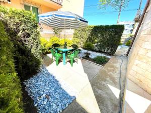 um pátio com uma mesa e um guarda-chuva em Emma and Armin Apartments & Garden em Eforie Nord