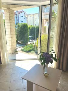 um vaso de flores sobre uma mesa em frente a uma janela em Emma and Armin Apartments & Garden em Eforie Nord