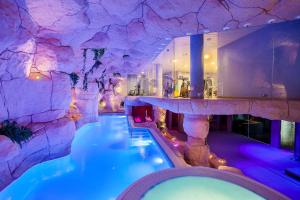a swimming pool in a mountain themed room with a rock wall at Hotel Beverly Park & Spa in Blanes