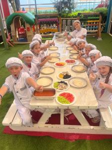a group of children standing around a table with food at Orange County Belek in Belek