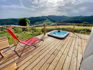 a deck with a red chair and a swimming pool at Yourte 2-4 personnes avec SPA in Saint-Laurent-de-Lévézou