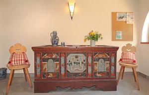 une armoire en bois avec deux chaises dans une pièce dans l'établissement Niglutsch Apartement Kastelruth, à Castelrotto