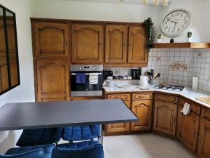 a kitchen with wooden cabinets and a clock on the wall at Maison de Charme, proche Paris, Maison Laffitte, gare Sartrouville in Sartrouville