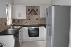 a kitchen with white cabinets and a stainless steel refrigerator at 2 bed Apartment Ballycastle Seconds to Seafront in Ballycastle