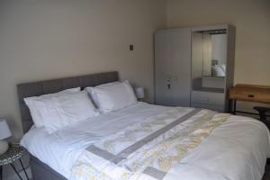 a large bed in a bedroom with a mirror at 2 bed Apartment Ballycastle Seconds to Seafront in Ballycastle