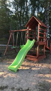 einen Spielplatz mit Rutsche und Schaukel in der Unterkunft Słonik in Stegers