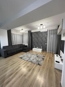 un soggiorno con divano nero e pavimenti in legno di ydr residence a Mamaia