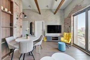 uma sala de estar com uma mesa e cadeiras e uma televisão em Grano Residence - Pool, Sauna, SPA & Parking by Downtown Apartments em Gdansk
