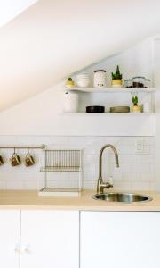 a kitchen with a sink and white walls and shelves at The Flats East in Wellington