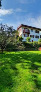 budynek z zielonym polem przed nim w obiekcie Chambre d'hôtes avec piscine au calme dans maison Basque w mieście Ascain