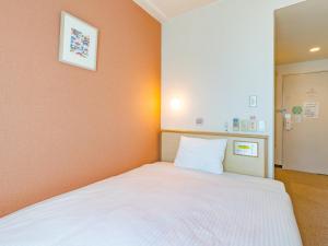 ein Schlafzimmer mit einem weißen Bett und einer orangefarbenen Wand in der Unterkunft Hotel Park Stadium Naha in Naha