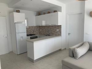 a kitchen with white cabinets and a white refrigerator at Charmant logement front port et Mer in Port El Kantaoui