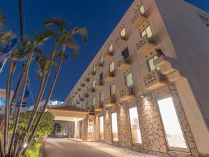 ein Gebäude mit Palmen davor in der Unterkunft Hotel Park Stadium Naha in Naha