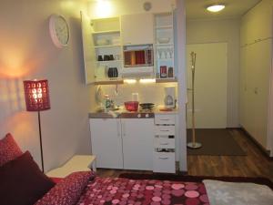 a small kitchen with white cabinets and a bed in a room at Piriko Piccolo Apartment in Rovaniemi