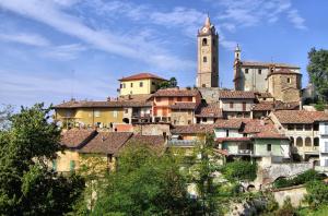 a town with a clock tower on a hill at Le Case della Saracca in Monforte dʼAlba