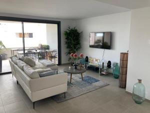 a living room with a white couch and a table at Appartement Casares - Mer, Golf, Piscine, Padel - FINCA CORTESIN in Estepona
