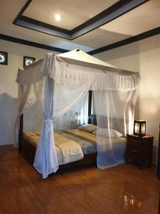 a bedroom with a canopy bed and a wooden floor at Five Time Homestay in Gili Islands
