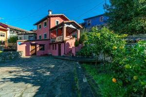 ein rosa Haus mit einem Orangenbaum davor in der Unterkunft Casa La Fuente Vibaño in La Sestal