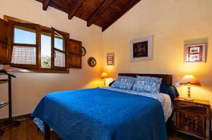 Schlafzimmer mit einem Bett mit blauer Bettwäsche und Fenstern in der Unterkunft Casa La Fuente Vibaño in La Sestal