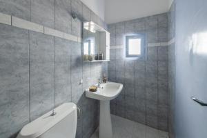 a bathroom with a sink and a toilet and a mirror at SantoriniNY in Perissa