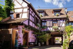 an old house with a pink facade with flowers at Schriner Hüss - Chambres d'hôtes & Gîtes in Beblenheim