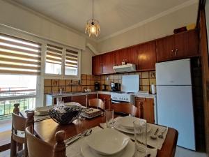 a kitchen with a table and a white refrigerator at Sea & Sun - 4th floor comfy apartment, great view in Preveza