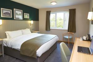 a hotel room with a bed and a desk with a laptop at Boat & Horses Inn in Oldham