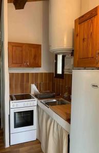 kuchnia z białą kuchenką i lodówką w obiekcie Le Gîte du Truel w mieście Mars