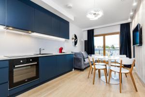 a kitchen with blue cabinets and a table and chairs at Uroczy Apartament w Centrum Starego Miasta in Gdańsk