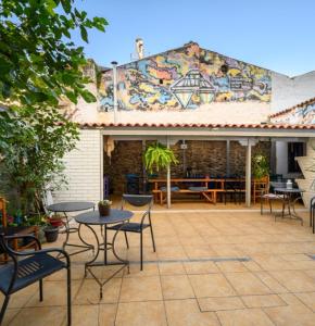 een patio met tafels en stoelen en een muurschildering bij Dioskouros Hostel in Athene