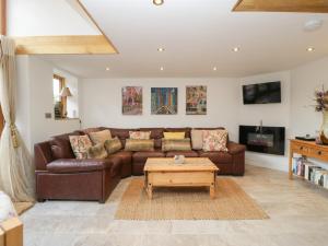 a living room with a brown leather couch and a coffee table at The Cart Barn in Leominster