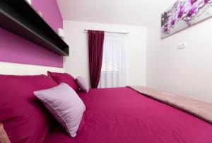 um quarto com uma cama rosa com lençóis e almofadas roxos em App Kokotić em Čižići