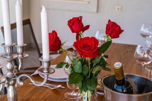 a table with red roses in a vase and candles at House Abatros in Babino Polje