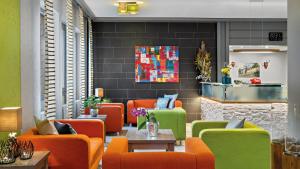 a lobby with orange and green chairs and a table at Hotel Diehlberg in Olpe