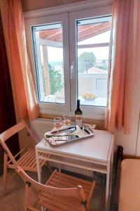 a table with two glasses of wine and a window at En Zar Ξυλόκαστρο in Áno Kamárion