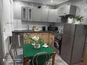 Silver Apartment Mazury Giżycko في غيجيتسكو: مطبخ مع طاولة خضراء وثلاجة