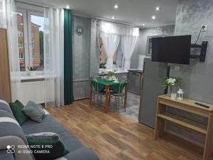 Silver Apartment Mazury Giżycko في غيجيتسكو: غرفة معيشة مع أريكة ومطبخ مع طاولة