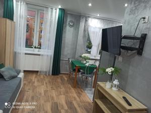 Silver Apartment Mazury Giżycko في غيجيتسكو: غرفة معيشة مع أريكة وطاولة وتلفزيون