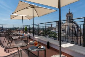 einen Balkon mit Stühlen und Tischen mit Blick auf ein Gebäude in der Unterkunft H10 Palazzo Galla in Rom