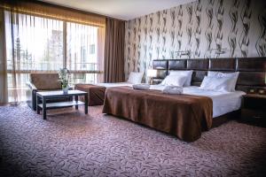 a hotel room with two beds and a chair at Zdravets SPA Hotel in Velingrad
