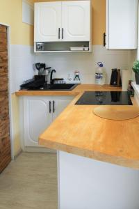a kitchen with white cabinets and a wooden counter top at Cozy Cottage in Sīkrags +3 photos