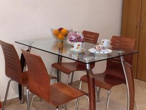 a glass table with chairs and a bowl of fruit on it at Comfy Alykes Apartment, Volos in Volos