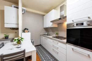 La cuisine est équipée de placards blancs et d'un four avec plaques de cuisson. dans l'établissement Casa Jessika, à Gardone Riviera