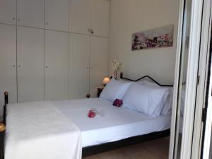 a bedroom with a white bed with two flowers on it at Comfy Alykes Apartment, Volos in Volos