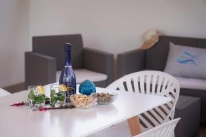 a white table with a bottle of wine and some snacks at Meraviglia d'Otranto in Otranto